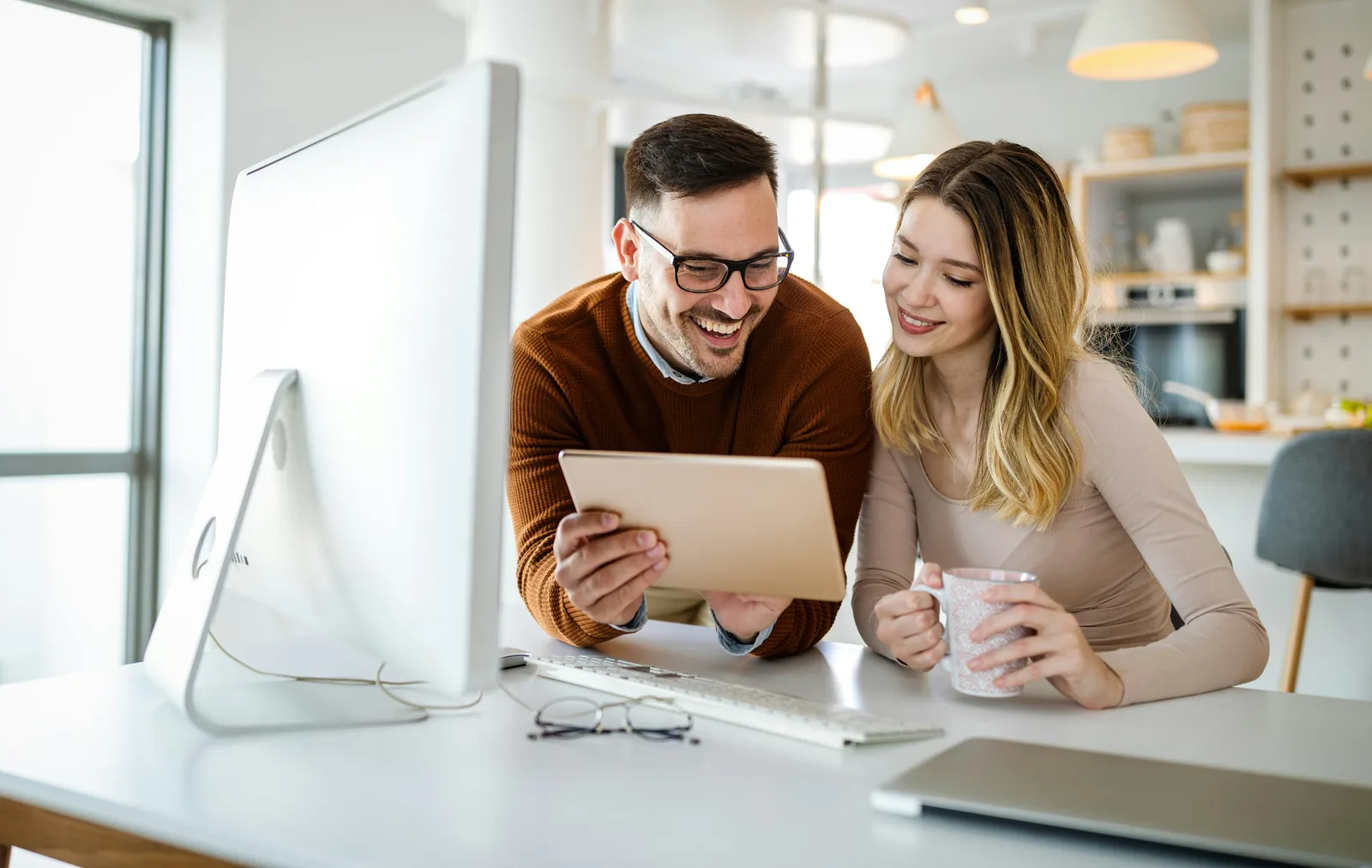 Deux entrepreneurs souriants utilisant une tablette pour développer leur activité en ligne avec Wavee